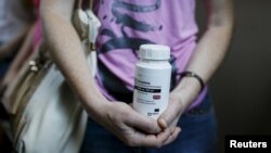 An activist of a non-governmental group, All- Ukrainian Network of People Living With HIV/AIDS, holds an empty package of the drug Aluvia, during a rally in Kyiv to protest the lack of government-supplied medicine, July 1, 2015.