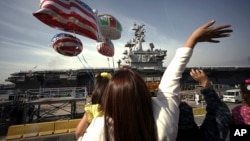 In this Oct. 1, 2015 file photo, family members of sailors wave as the U.S. Navy aircraft carrier USS Ronald Reagan arrives at a U.S. Navy base in Yokosuka, Japan south of Tokyo. (AP Photo/Eugene Hoshiko, File) 