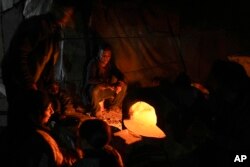 Displaced Palestinians sit next to a makeshift oven in a tent set up on an area in Deir al-Balah, Gaza Strip, Dec. 5, 2024.