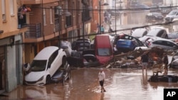 Los residentes observan los autos amontonados luego de ser arrastrados por las inundaciones en Valencia, España, el miércoles 30 de octubre de 2024. (Foto AP/Alberto Saiz).