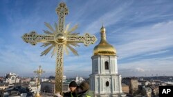 FILE — Ihor Kuzmenko, left, and Yuriy Maliuh altitude workers install a restored cross on a dome of Saint Sophia Cathedral in Kyiv, Ukraine, December 21, 2023.