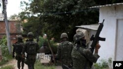 Soldiers on patrol walk through an alley at the Lins Complex of slums in Rio de Janeiro, Brazil, March 27, 2018. Thousands of troops and police are entering a complex of favelas in Rio de Janeiro in one of the largest operations since the military took control of security in the Brazilian city last month.