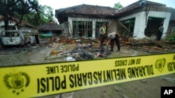 Polisi memeriksa rumah pengikut Ahmadiyah yang rusak setelah diserang sekelompok orang di Pandeglang, Banten, 7 Februari 2011. (Foto: AP)