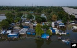 Huts, inhabited by farm workers, are inundated with water from the swollen Yamuna River in New Delhi, India, Wednesday, Aug. 9, 2023.