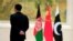 FILE - A member of the security personnel stands guard next to, from left, Afghan, Chinese and Pakistani flags during the first China-Afghanistan-Pakistan Foreign Ministers' Dialogue in Beijing, China, Dec. 26, 2017. 