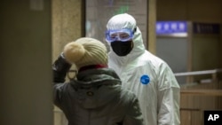 A worker wearing a hazardous materials suit checks a passenger at a subway station in Beijing, Jan. 24, 2020. 