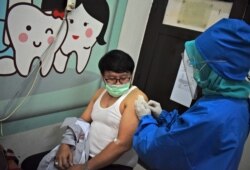 Seorang tenaga medis memberikan kandidat vaksin virus corona kepada seorang sukarelawan saat uji coba di sebuah puskesmas di Bandung, Jawa Barat, Indonesia, 14 Agustus 2020.