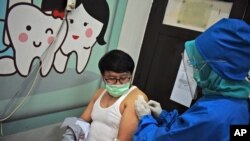 A medical worker gives coronavirus vaccine candidate to a volunteer during a trial at a community health center in Bandung, West Java, Indonesia, Aug. 14, 2020. 