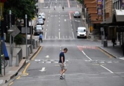 FILE - A man crosses a mostly empty city center street as people in Greater Brisbane have been ordered into lockdown as authorities try to suppress a growing coronavirus disease (COVID-19) cluster in Brisbane, Australia, March 30, 2021.