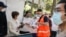 A staff member assists people waiting in line outside a coronavirus disease (COVID-19) vaccination center at Sydney Olympic Park during a lockdown to curb the spread of an outbreak in Sydney, Australia, Aug. 16, 2021. 
