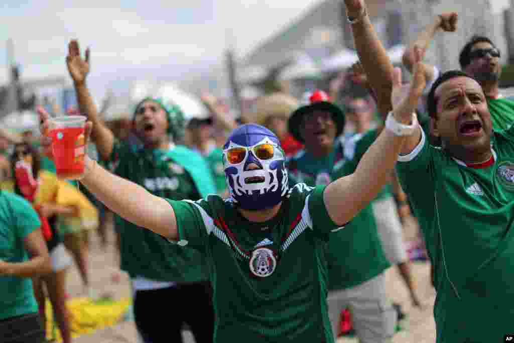 Apoiantes mexicanos ao rubro, usando máscaras de Luta Livre, depois do jogo contra os Camarões. Os mexicanos comemoraram a vitória no FIFA Fan Fest montado na praia de Copacabana no Rio de Janeiro, Brasil, Junho 13, 2014