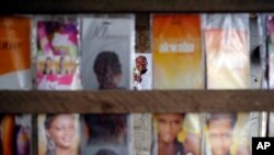 A poster of incumbent President Alassane Ouattara, center rear, is seen at a local hair dressing salon in Abidjan, Ivory Coast, Oct. 21, 2015.