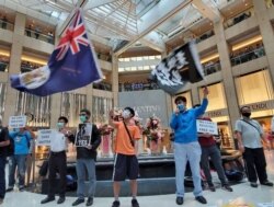 Activists chant slogans, display a British colonial flag and banners at a protest in Landmark shopping mall, June 9, 2020.