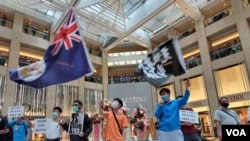 Activists chant slogans, display a British colonial flag and banners at a protest in Landmark shopping mall, June 9, 2020. (VOA) 
