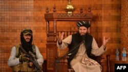 তালিবান ক্ষমতা দখলের পর কাবুলের আবদুল রহমান মসজিদে একজন সশস্ত্র তালিবান সেনার উপস্থিতিতে জুম্মার নামাজের খুতবা পড়ছেন ইমাম