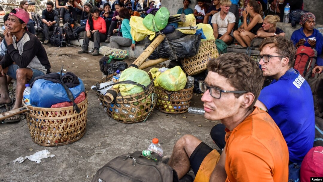 Người leo núi nước ngoài và Indonesia ngồi nghỉ ở làng Sembalun khi tìm đường xuống núi Rinjani hôm 29/7.
