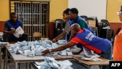 Funcionários da assembleia de voto organizam os boletins de voto antes de procederem à contagem numa assembleia de voto em Windhoek, Namíbia, em 1 de dezembro de 2024, durante a votação alargada após as eleições gerais do país. 