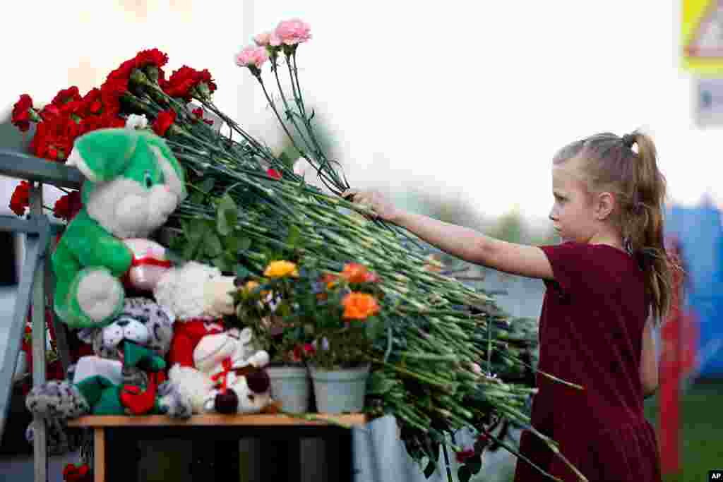 در محل یادبود قربانیان تیراندازی در یک مدرسه در کازان روسیه، یک دختربچه گل میگذارد.