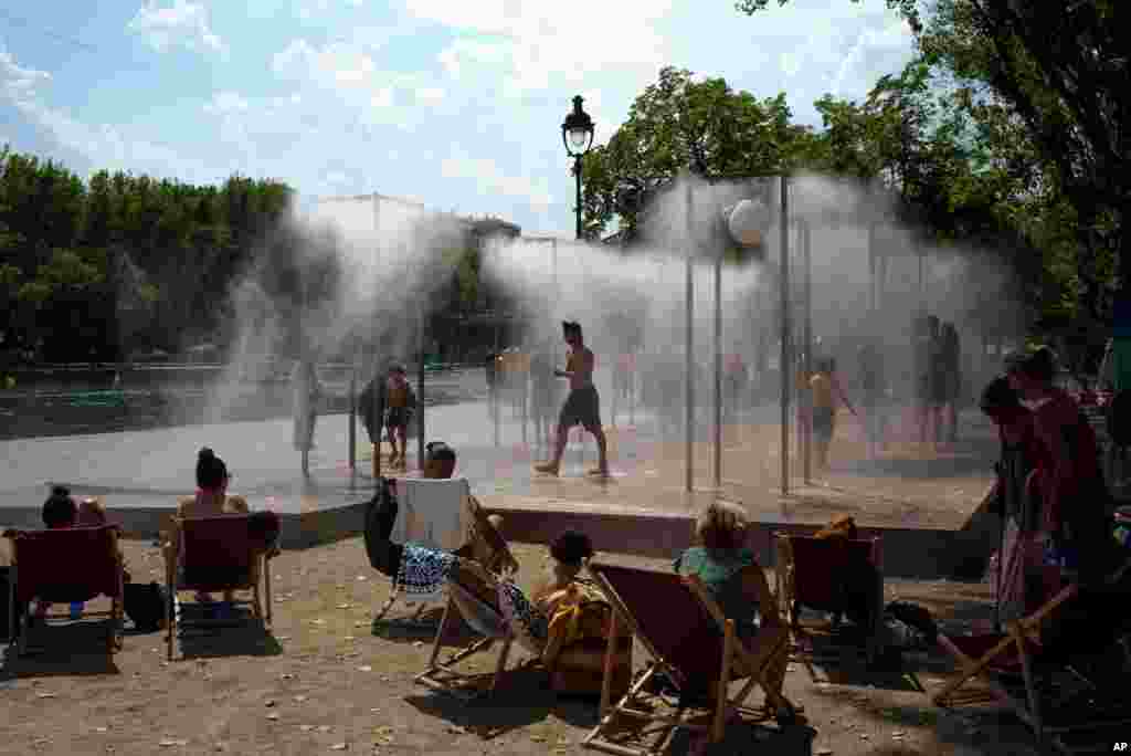 People cool off under a fountain along the Canal de l&#39;Ourcq in Paris, France.