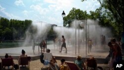 People cool off under a fountain along the Canal de l'Ourcq in Paris, France.