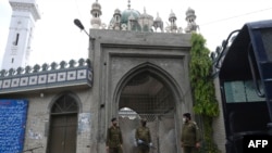 Policemen wearing facemasks stand guard outside a closed mosque during Friday prayers on a government-imposed nationwide lockdown as a preventive measure against the COVID-19 coronavirus, in Lahore on April 17, 2020.