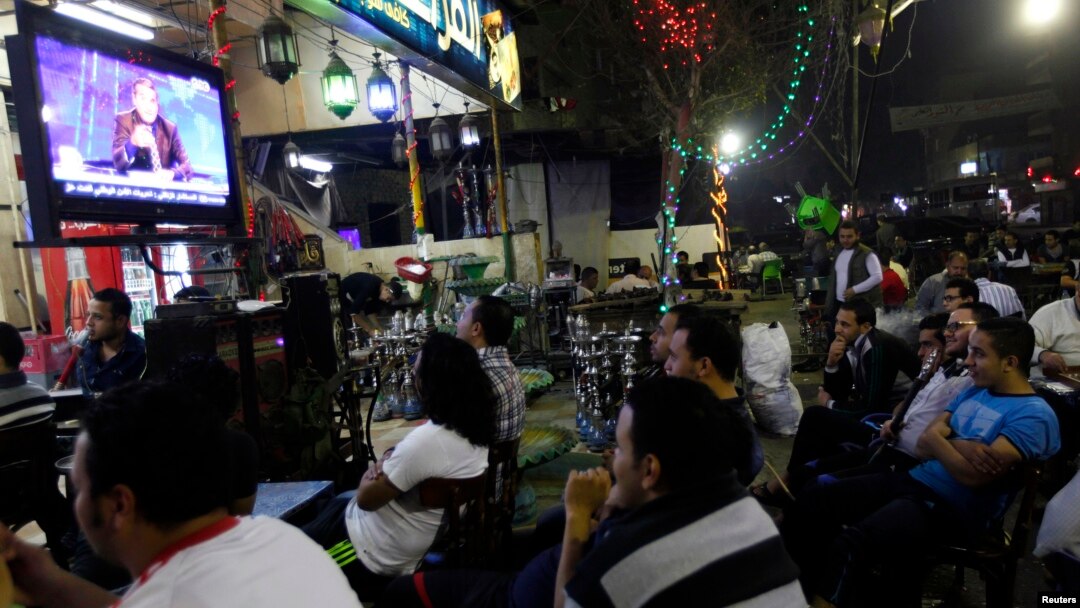 Egyptians watch the first episode of a show by Egypt's most prominent television satirist, Bassem Youssef, called "Al-Bernameg" (The Programme) in Cairo, Oct. 25, 2013. 