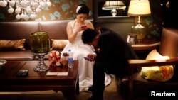 A couple waits to participate in a staged mass wedding, organised as part of a matchmaking event to inspire singles to get married, in a suburban area of Shanghai May 18, 2013. 