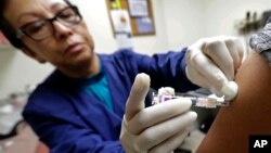 Ana Martinez, a medical assistant at the Sea Mar Community Health Center, gives a patient a flu shot, Jan. 11, 2018 in Seattle. According to an update by the Centers for Disease Control and Prevention, the flu is now widespread in every state except Hawaii. (AP Photo/Ted S. Warren) 