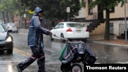 FILE - A United States Postal Service (USPS) mail carrier walks through heavy rain in Jersey City, New Jersey, July 10, 2020.