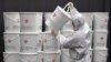 A worker in protective gear stacks plastic buckets containing medical waste from coronavirus patients at a medical center in Daegu, South Korea.