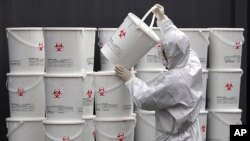 A worker in protective gear organizes plastic containers of medical waste from coronavirus patients at a medical center in Daegu, South Korea.