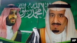 A man walks past a banner showing Saudi King Salman, right, and his Crown Prince Mohammed bin Salman, outside a mall in Jiddah, Saudi Arabia, March 7, 2020.