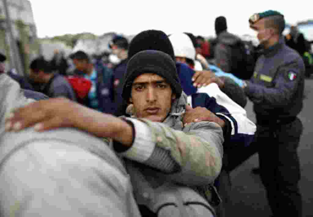 A man fleeing the unrest in Tunisia looks on as he and others arrive at the southern Italian island of Lampedusa (file photo)