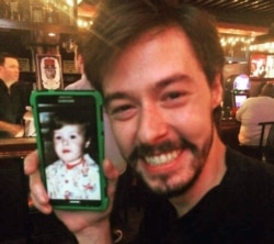 Luke Vincent holds up a phone with a picture of himself as a toddler. (Courtesy - Luke Vincent)