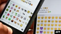 FILE - Emoji characters are shown on the screens of two mobile phones in Paris, Aug. 6, 2015.