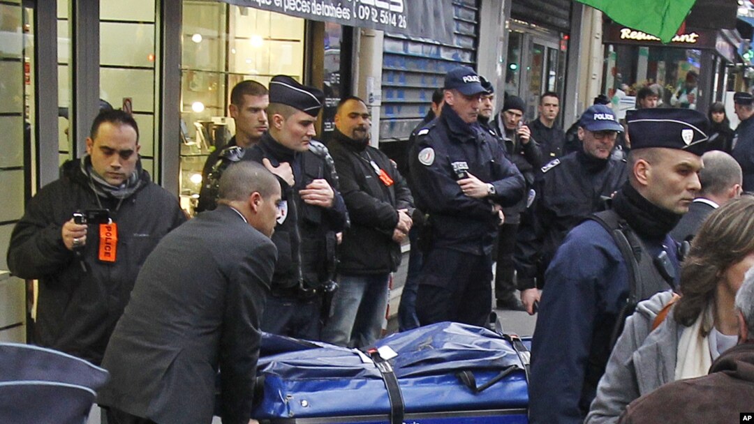Petugas membawa 3 jenazah aktivis Kurdi yang ditembak tewas di Paris, sementara polisi melakukan penjagaan di lokasi penembakan, Kamis (10/1). 