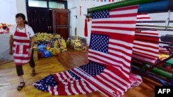 A Chinese employee walks past newly made U.S. flags at a factory in Fuyang in China's eastern Anhui province, July 13, 2018. As the U.S.-China trade war rages, a factory set amid corn and mulberry fields in central China stitches together U.S. and "Trump 