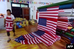 FILE - A Chinese employee walks past new U.S. flags at a factory in Fuyang in China's eastern Anhui province, July 13, 2018. China says its factory production is the weakest in 17 years.