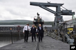 FILE - Britain's Prime Minister Boris Johnson, right, visits the nuclear submarine HMS Victorious with Defence Secretary Ben Wallaceat, centre, and Commander Justin Codd, left, at the Naval Base in Faslane, Scotland, July 29, 2019.