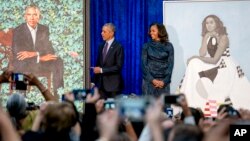 Former President Barack Obama and former first lady Michelle Obama stand on stage together as their official portraits are unveiled at a ceremony at the Smithsonian's National Portrait Gallery, Feb. 12, 2018, in Washington.