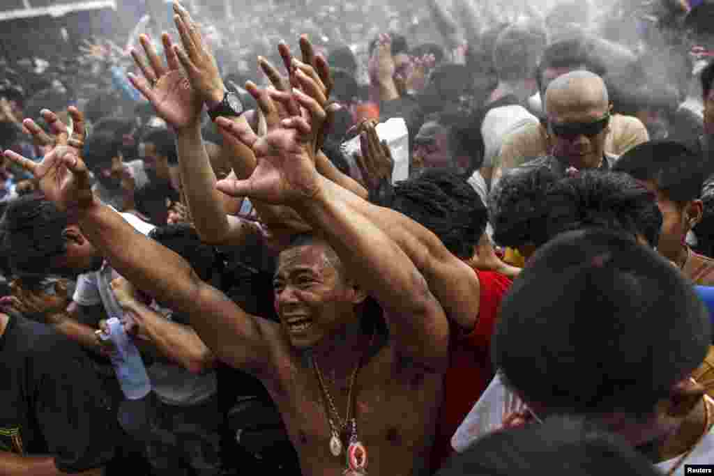 Devotees react as Buddhist monks spray holy water during the annual Magic Tattoo Festival at Wat Bang Phra in Nakhon Prathom province, Thailand.