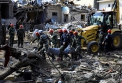 Search and rescue teams carry the body of a victim from the blast site hit by a rocket during the fighting over the breakaway region of Nagorno-Karabakh in the city of Ganja, Azerbaijan, Oct. 11, 2020.