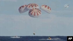 This image provided by NASA shows SpaceX's Dragon capsule carrying a test dummy splashed down into the Atlantic ocean off the Florida coast, Friday, March 8, 2019. (NASA via AP)