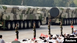 FILE - Military vehicles carrying intercontinental ballistic missiles travel past Tiananmen Square during the military parade marking the 70th founding anniversary of People's Republic of China, on its National Day in Beijing, China, Oct. 1, 2019.