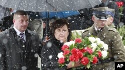 Poland's first lady Anna Komorowska (C) walks to lay flowers during a ceremony at the site of a plane crash that killed former Poland's President Lech Kaczynski and 95 others near the Russian city of Smolensk, April 9, 2011