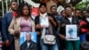 FILE - People hold photos of disappeared or deceased relatives in front of the president's office as they gather to present a list of people who disappeared during demonstrations against government-proposed tax hikes, in Nairobi, Kenya, Sept. 24, 2024.