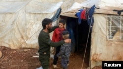 FILE - Ahmad Hamra is pictured with his children outside of a tent at an internally displaced Syrian camp, in northern Aleppo, near the Syrian-Turkish border, Syria, Feb. 17, 2021. 