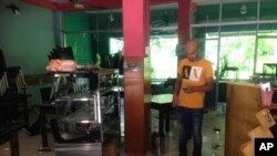 Mohamed Ramzeen makes a call from his mobile phone standing in his vandalized small restaurant in Pilimathalawa, Sri Lanka, Thursday, March 8, 2018.