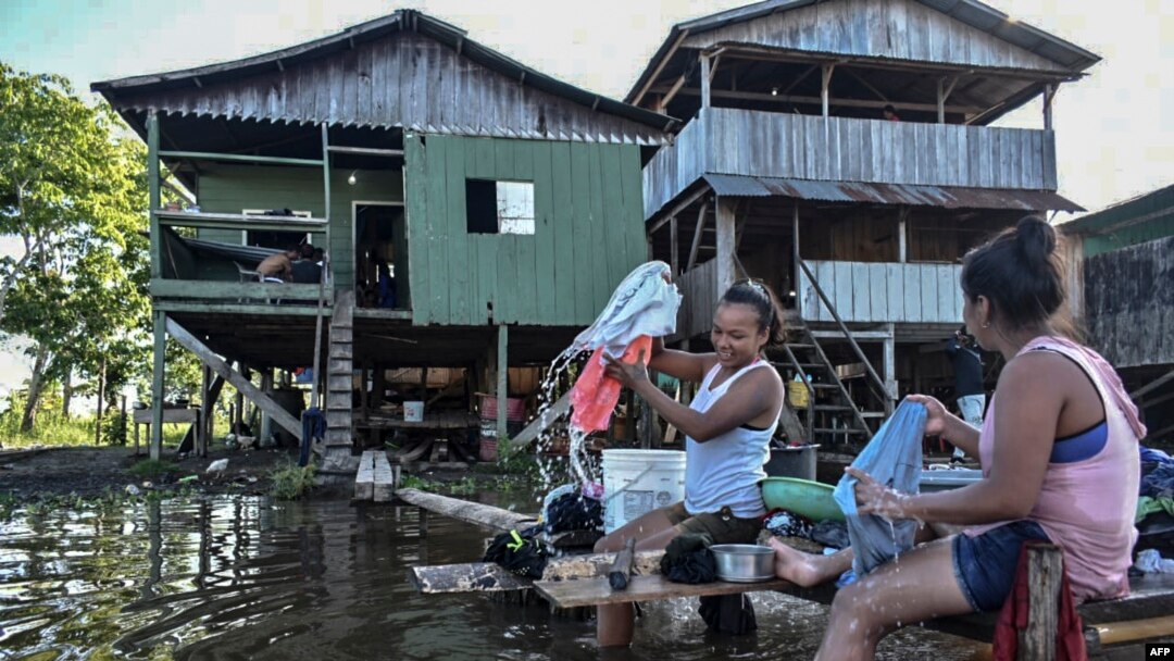 Women wash clothes at the Amazon river in Leticia, Colombia, on May 13, 2020, amid the new coronavirus pandemic. 