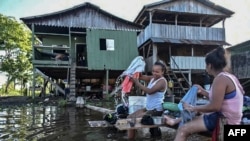 Warga di Leticia, Kolombia mencuci pakaian mereka di tepi sungai Amazon, 13 Mei 2020. Pemerintah Kolombia memperketat restriksi di kawasan ini, untuk menghentikan kenaikan jumlah kasus baru virus corona, Kamis malam (14/5).